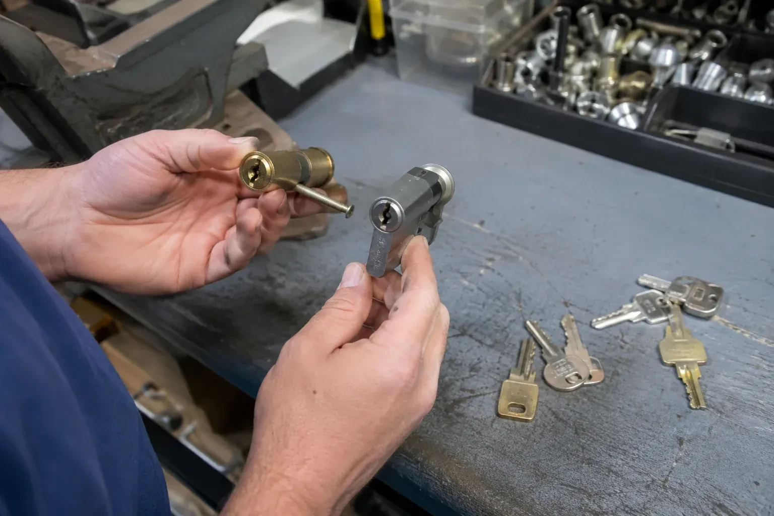 Hands comparing detached lock cylinders beside loose keys on a workbench. — Broken Key Extraction, Newmarket